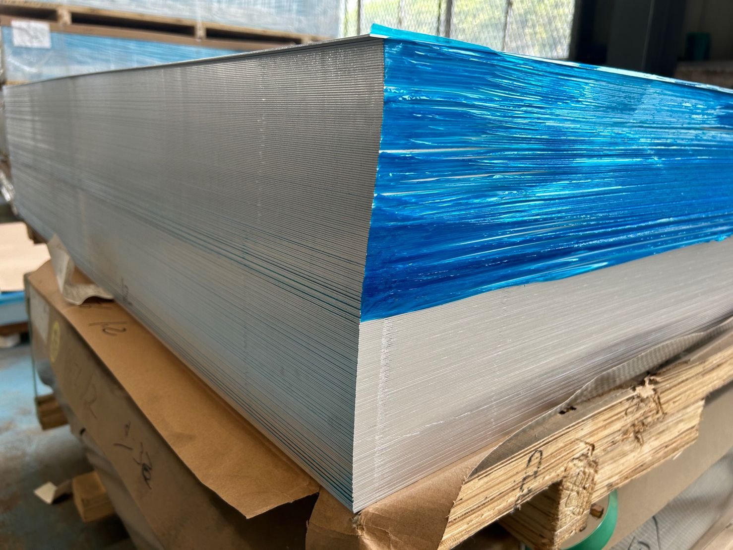 Local reference photograph showing closely stacked aluminum sheet edges and blue protective film